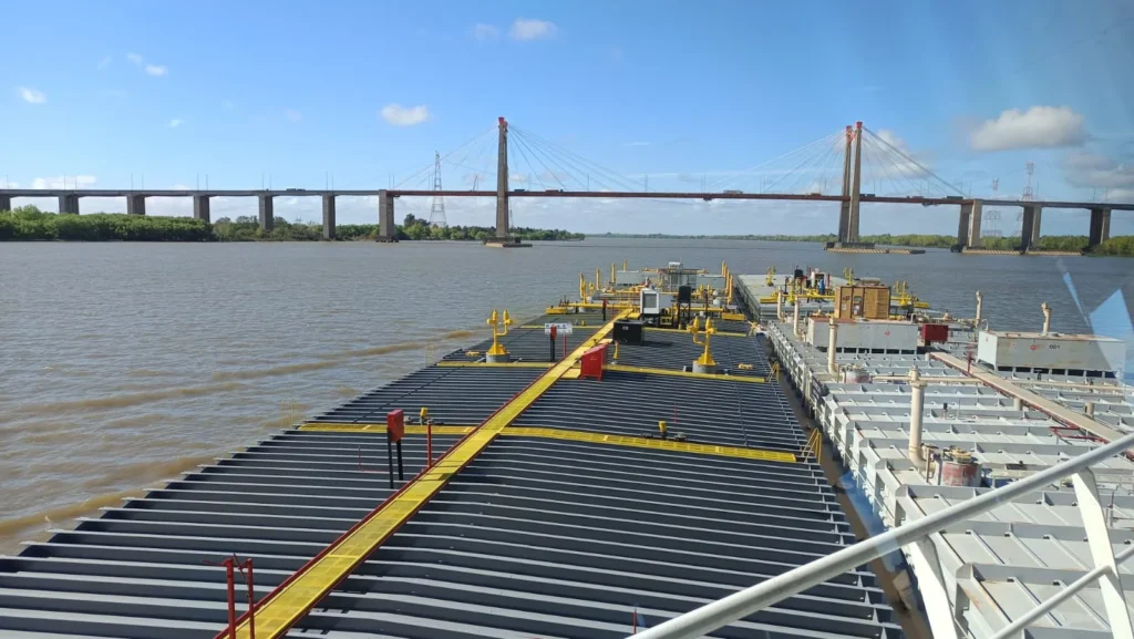 Convoy of tank barges heading downriver on the Paraná under the Rosario–Victoria bridge
