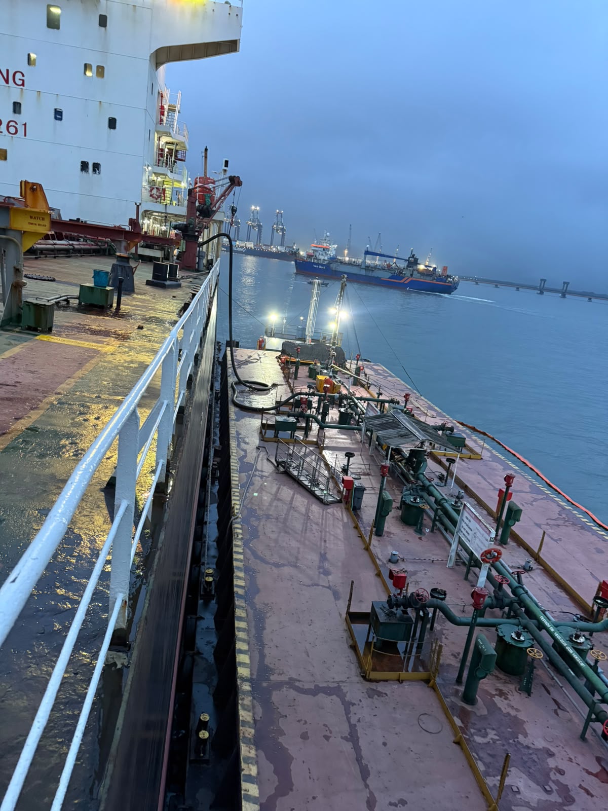 Bunker barge alongside at first light, hoses connected